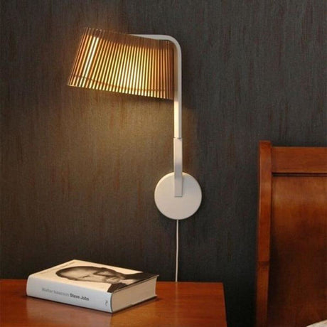 LED Owalo 7030 wall light made of wood 47 cm on a wall above a bedside table with a book.