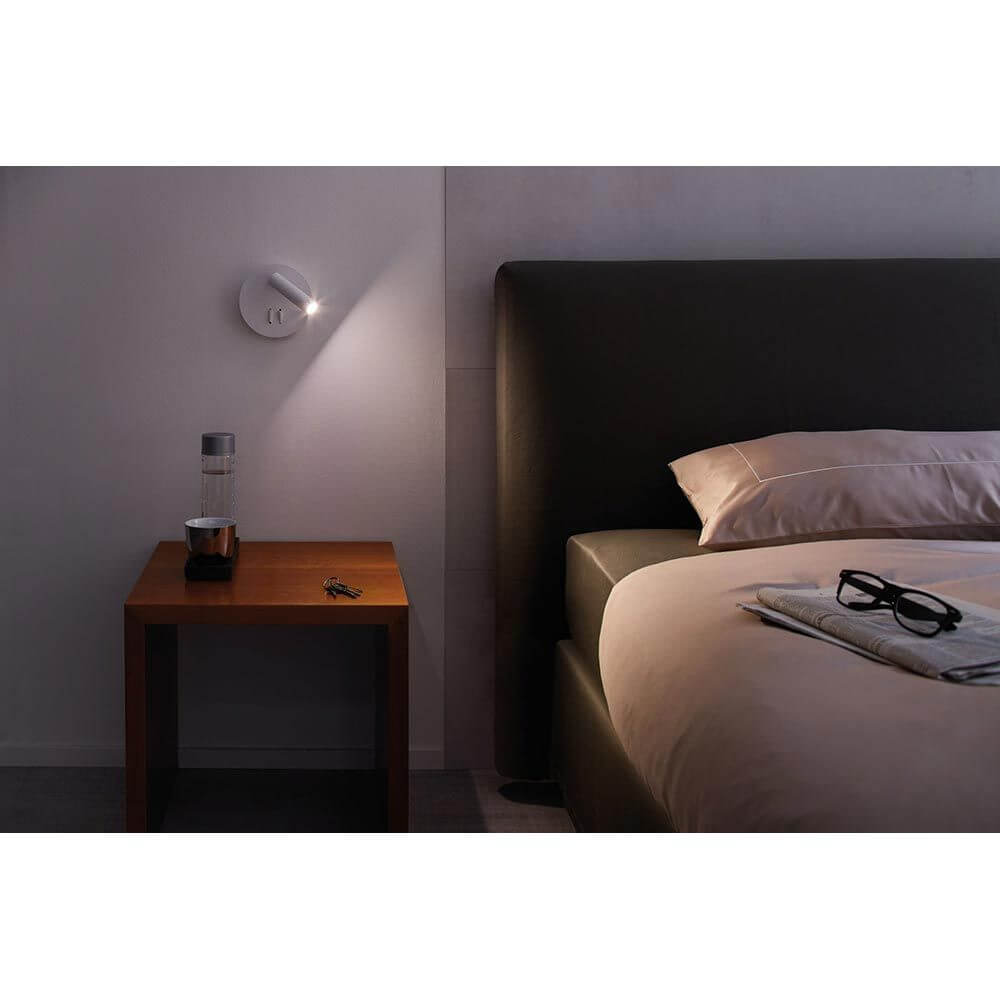 LED Wandleuchte Tabari Weiß, Chrom neben einem Bett auf einem Nachttisch, optimale Leselampe.