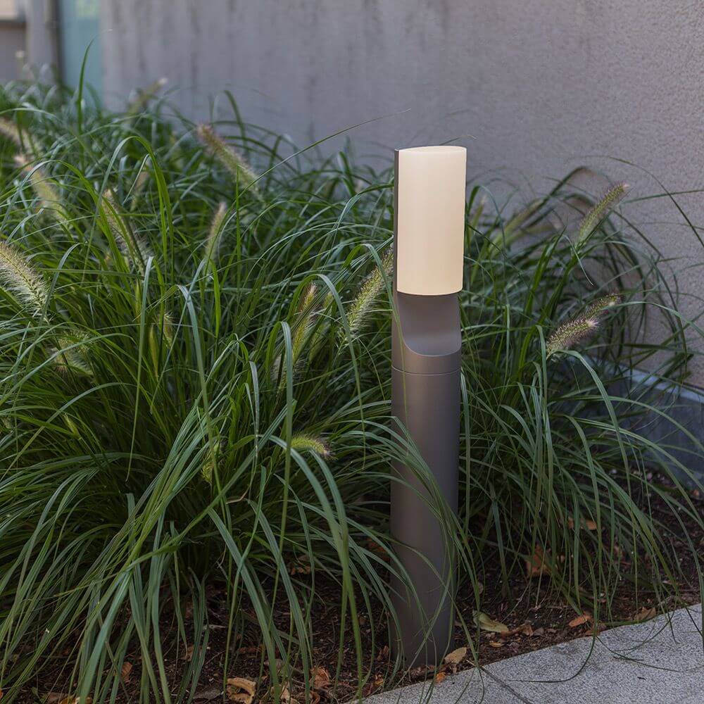 LED Wegeleuchte Bati IP44 65cm Anthrazit vor grünen Pflanzen im Außenbereich.