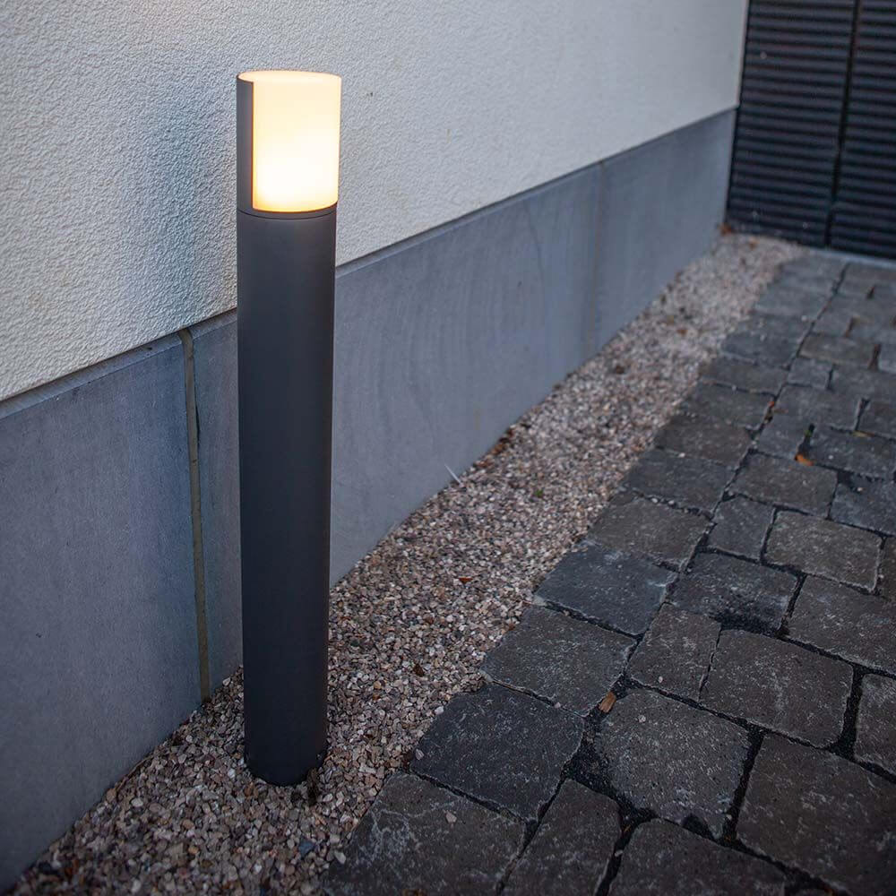 LED-Wegeleuchte Cyra mit drehbarem Kopf neben einem gepflasterten Weg.