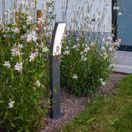 LED-Wegeleuchte Kira Anthrazit IP54 vor bunten Blumen im Garten.