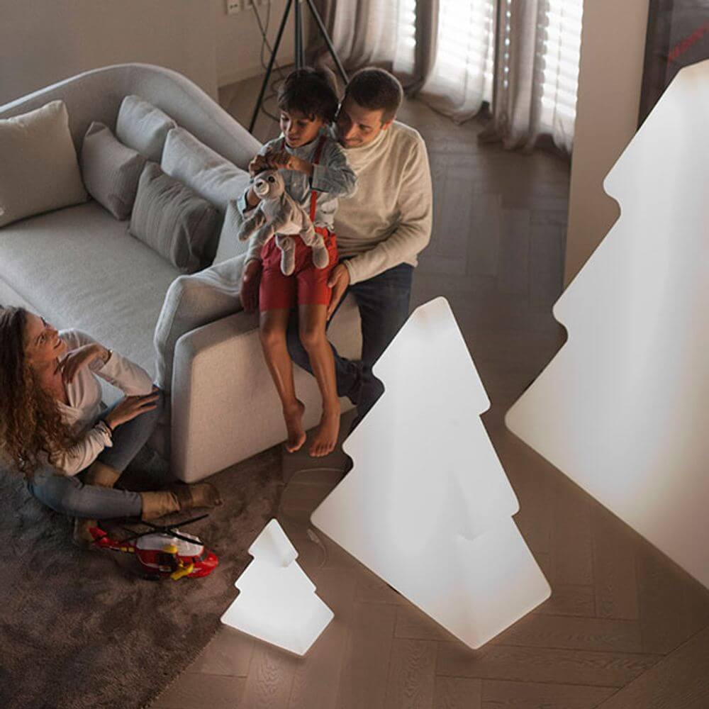 Familie genießt eine winterliche Atmosphäre mit leuchtenden Weihnachtsbäumen im Wohnzimmer.