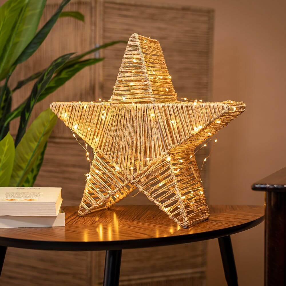 LED Akku-Weihnachtsstern Sisine Star IP54 auf Tisch mit warmweißen Lichtern, aus Naturgeflecht Seegras gefertigt.