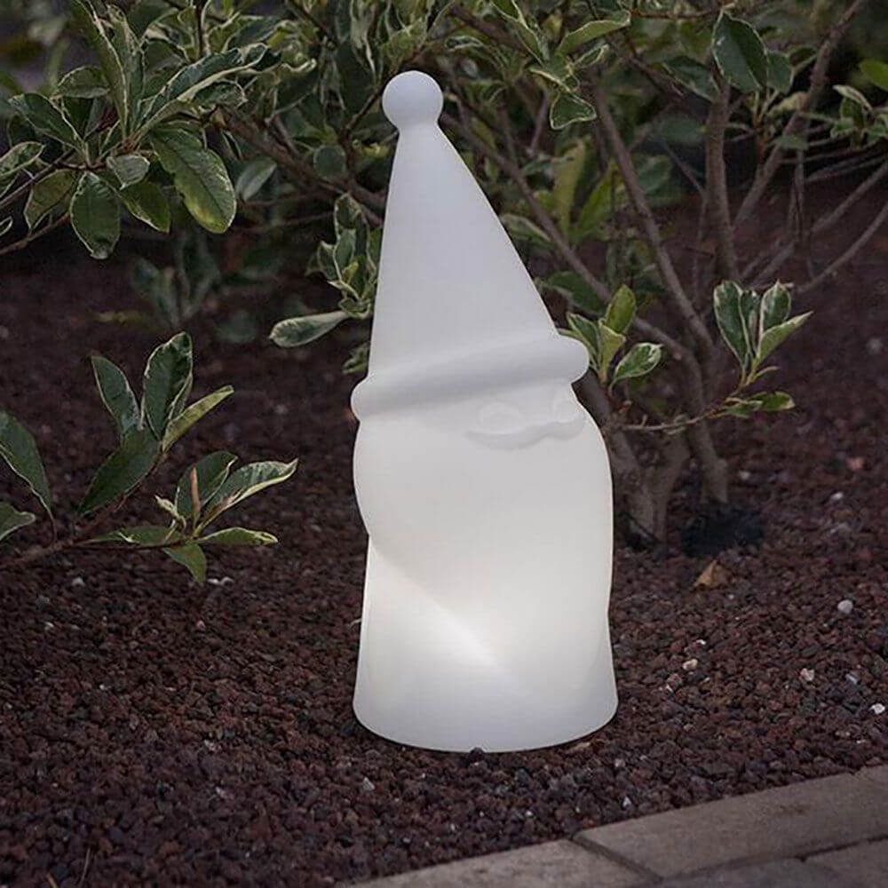 LED Weihnachtszwerg Amelio Akku + Solar IP65 leuchtend im Garten zwischen Pflanzen.