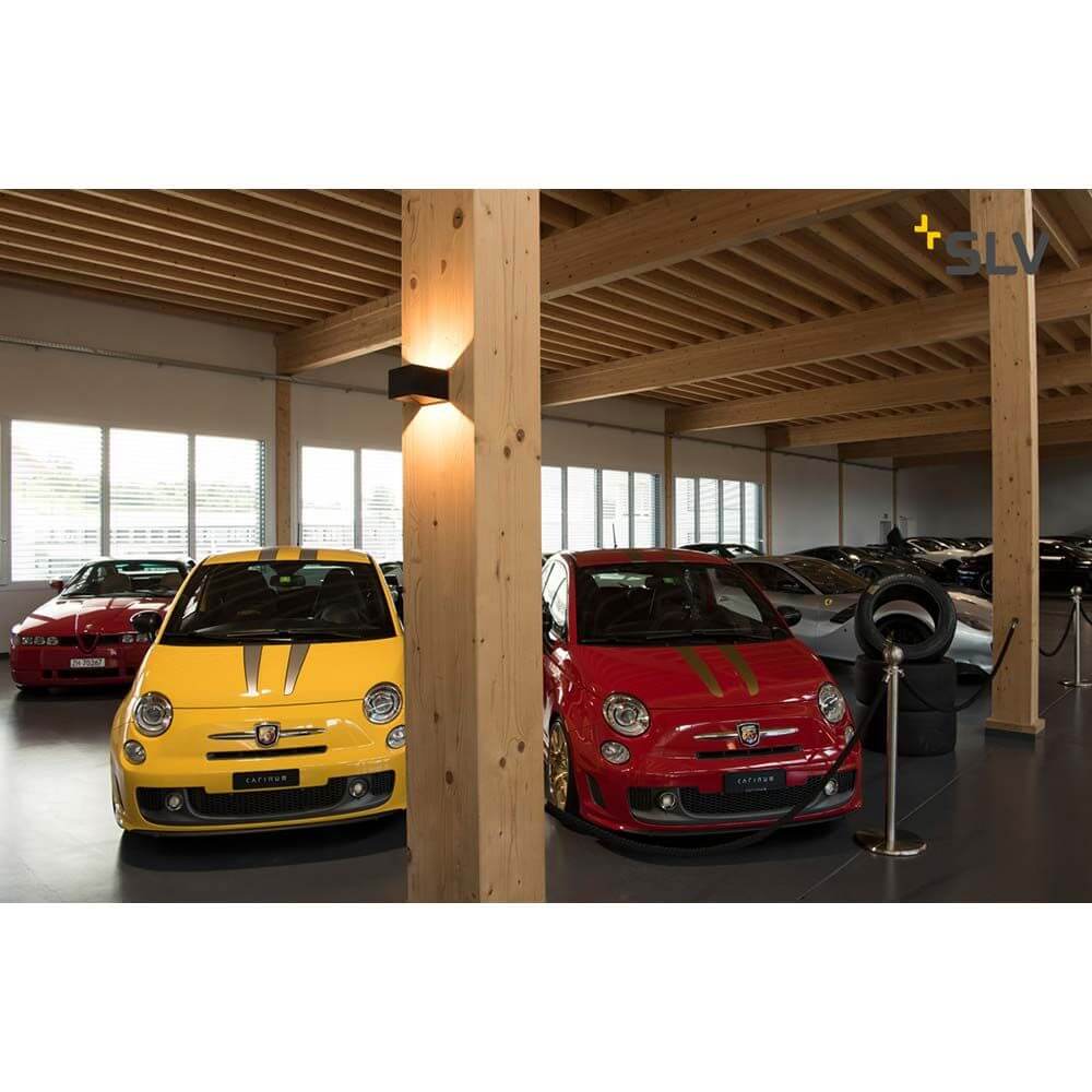 Zwei bunte Autos in einer modernen Garage, beleuchtet von stilvollen Wandlampen.