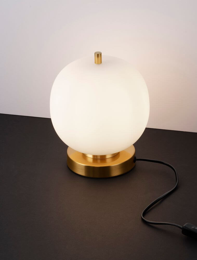 Lato Tischleuchte E14 Ø 18,5cm auf schwarzem Tisch mit opalglas Kugel und goldener Basis.