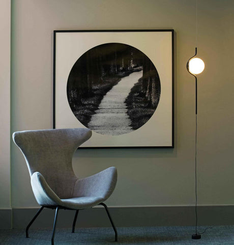 Le Vita LED Hänge- & Stehlampe 118cm Schwarz neben einem modernen Sessel und kreativem Wandbild.