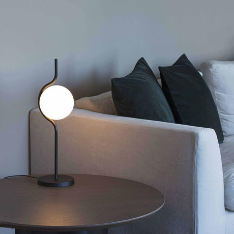 Le Vita LED Tischlampe Touch-Dimmer Schwarz auf einem Tisch neben einem Sofa mit Kissen.
