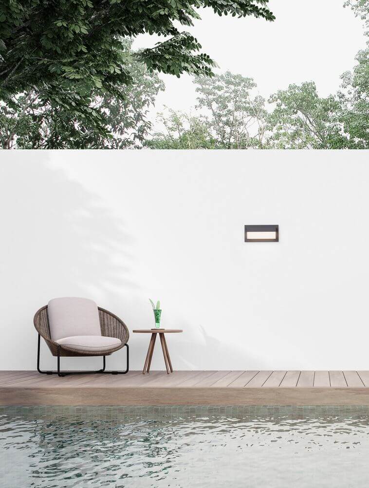 Leto LED Außenwandleuchte Horizontal 3000K Schwarz IP65 an einer Wand neben einem Sitzbereich und schwimmenden Pool.