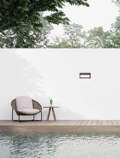 Leto LED outdoor wall light Horizontal 3000K Black IP65 on a wall next to a seating area and swimming pool.