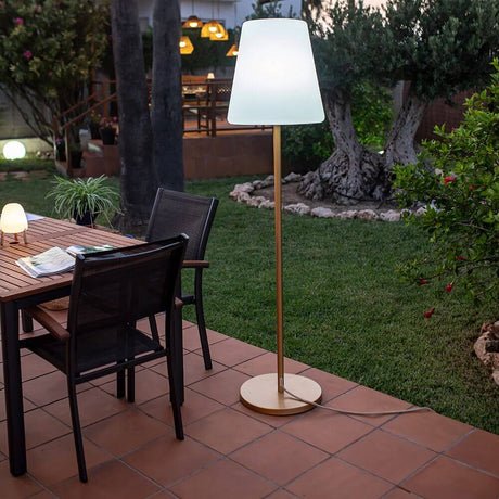 Lampadaire à accu Lola Big avec télécommande en extérieur à côté d’une table, idéal pour des soirées pleines d’ambiance.