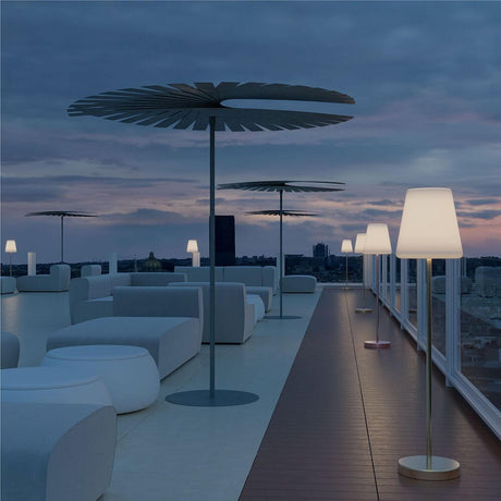 LED Draadloze vloerlamp Lola Mini met afstandsbediening op een stijlvol terras bij zonsondergang.