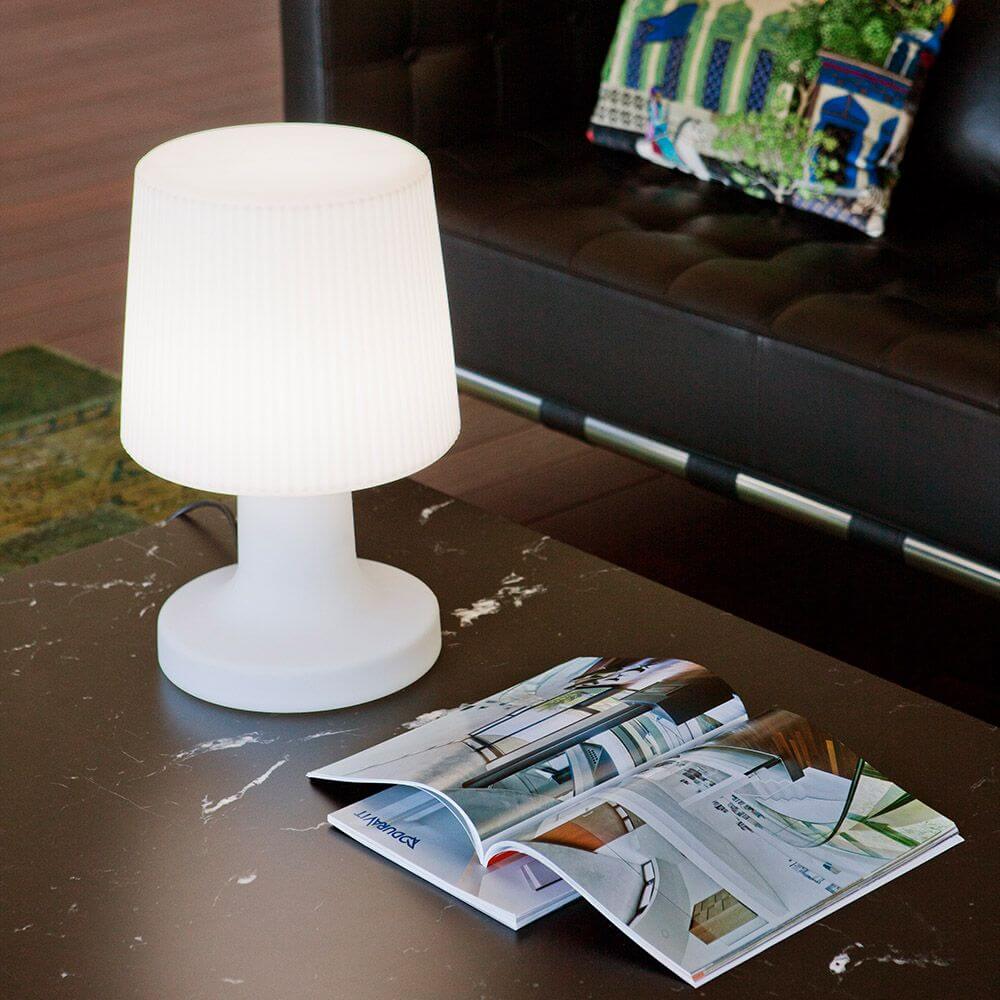 LED-Akku-Tischleuchte Carmen 45cm mit Fernbedienung auf einem Tisch neben einem Magazin.
