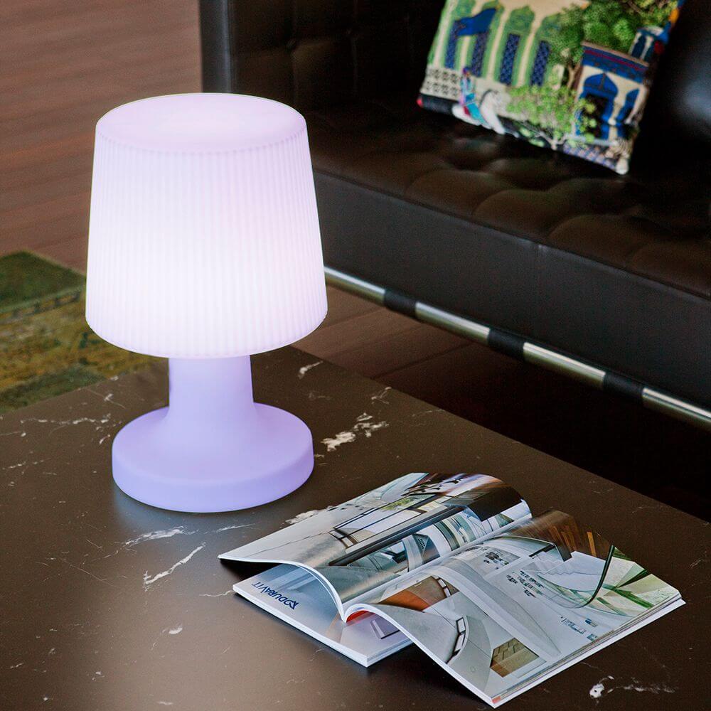 LED-Akku-Tischleuchte Carmen 45cm mit Fernbedienung auf einem Tisch neben einem Magazin.