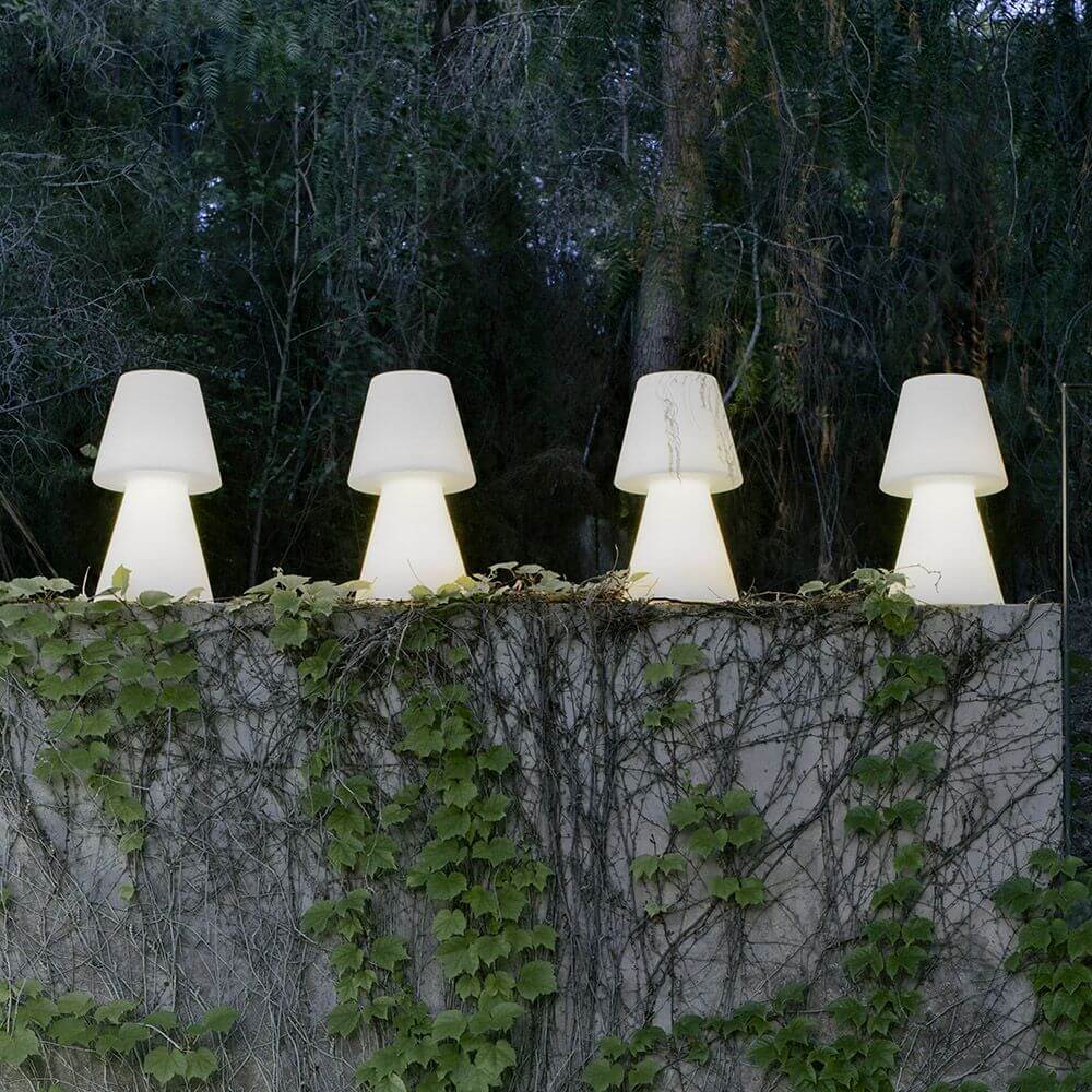 LED-Akku-Tischleuchte Lola Large mit Fernbedienung dekorative Beleuchtung im Garten zwischen Pflanzen.