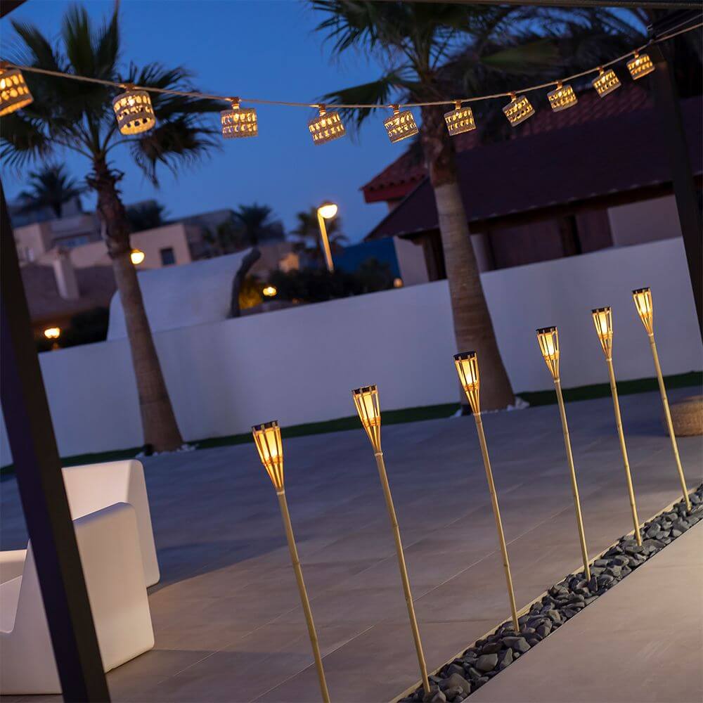 Alba LED Biergarten Lichterkette in warmem Licht über elegantem Außenbereich mit Palmen.