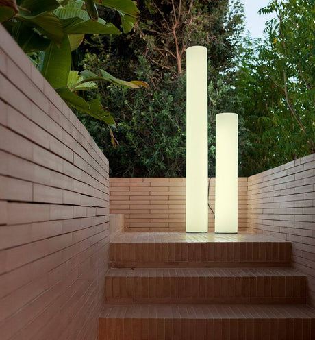 Outdoor floor lamp Fity Big on a staircase in a green garden.