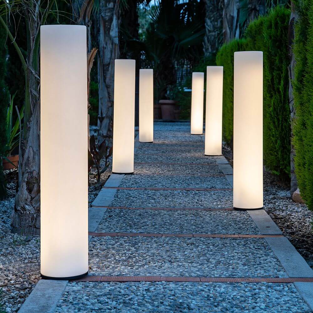 Außen-Stehleuchte Fity Mini auf einem Gehweg, umgeben von Pflanzen, bietet elegantes Licht für Garten und Terrasse.