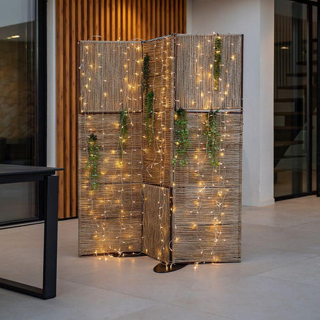 Biombo Milos Stellwand aus Jute mit Lichterketten und natürlichen Akzenten in modernem Raum.