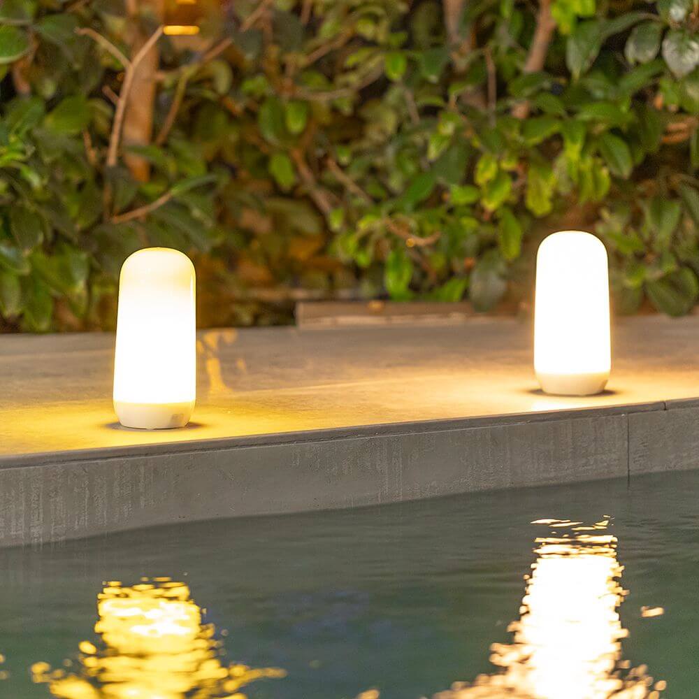 Zwei Candy Akku-Tischleuchten mit Flammen-Effekt am Pool, gemütliches Licht für den Außenbereich.