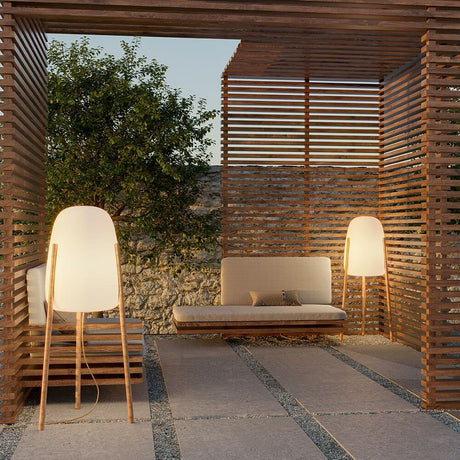 Tripod floor lamp Rocket in a modern outdoor area with wood cladding and a cozy seating area.