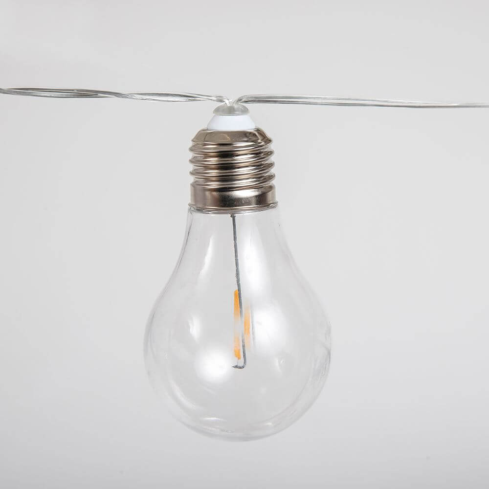 Transparente Glühbirne der kabellosen Girlande Stella Solar, umgeben von Draht.