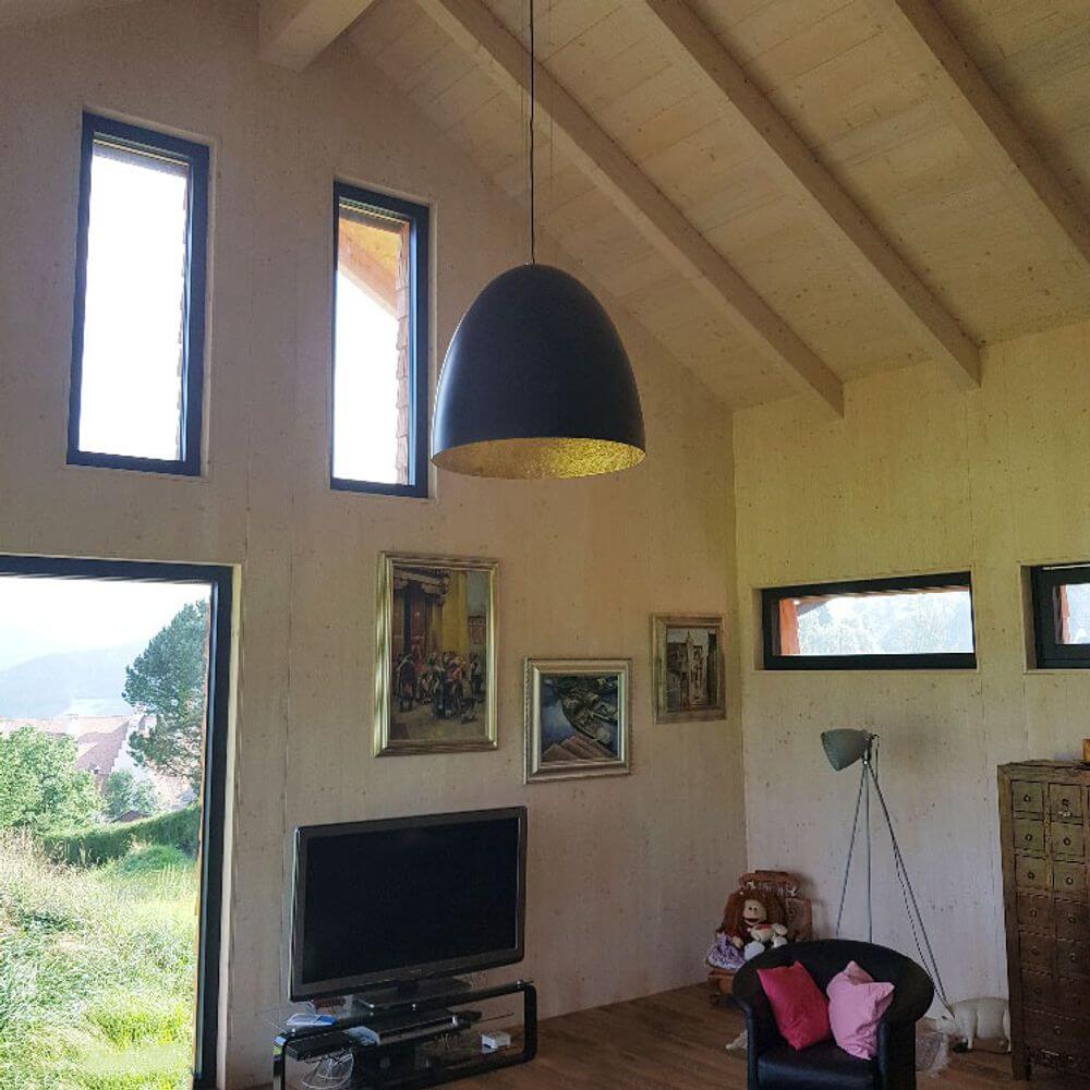 Hängeleuchte Egg XL Ø 75cm Schwarz, Goldfarben in modernem Wohnraum mit Holzdecke.