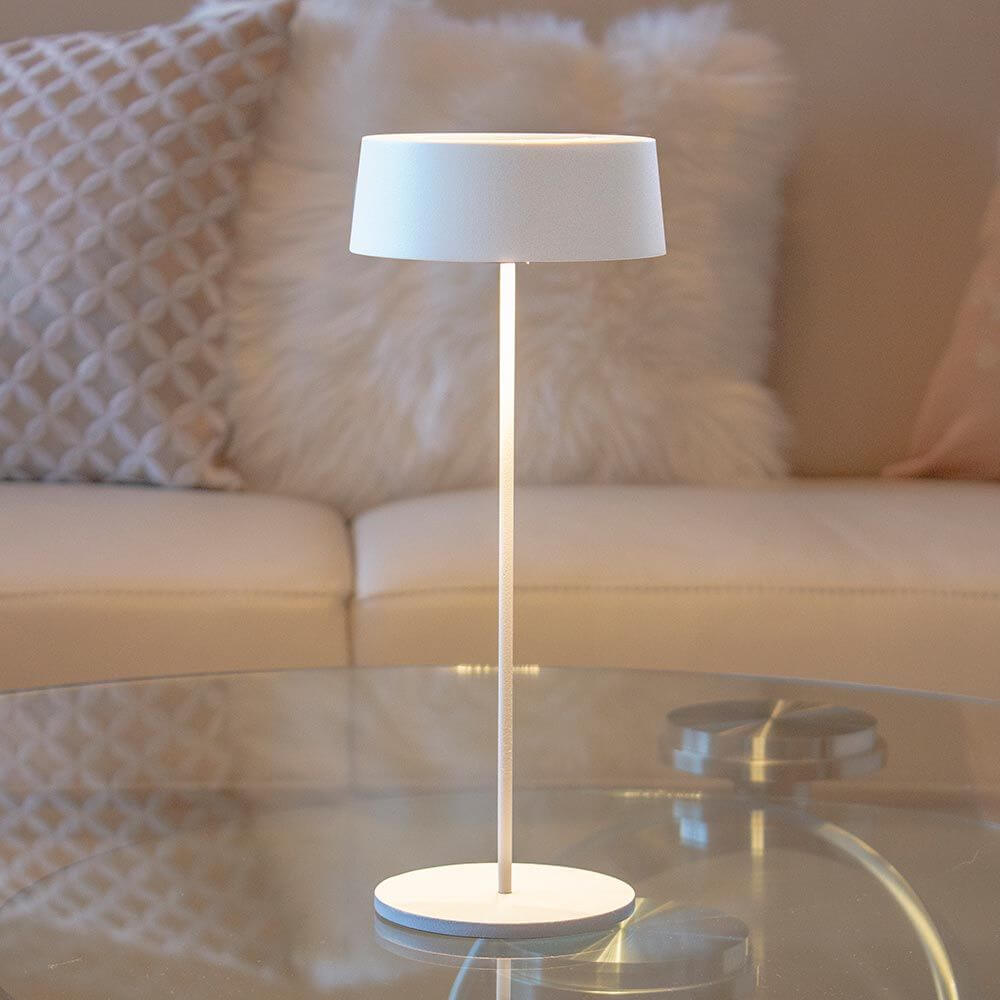 Moderne weiße LED-Akkuleuchte Cocktail auf einem Tisch in einem eleganten Wohnzimmer.