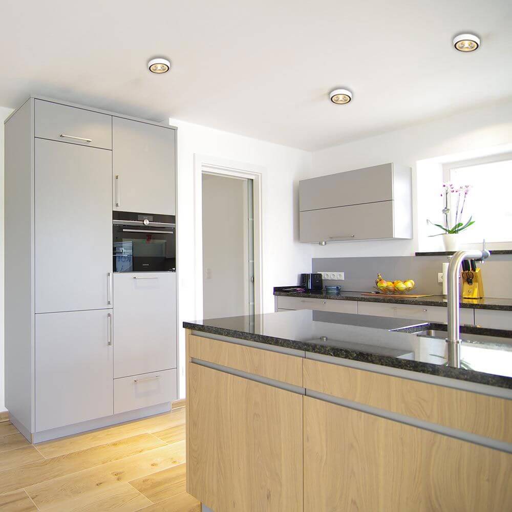 Moderne Küche mit LED Deckenstrahlern und eleganten Holz- und grauen Möbeln.