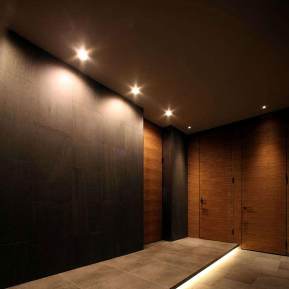 Flache LED Außer-Aufbauspot IP65 im eleganten Flur mit warmweißem Licht und schicker Holzverkleidung.