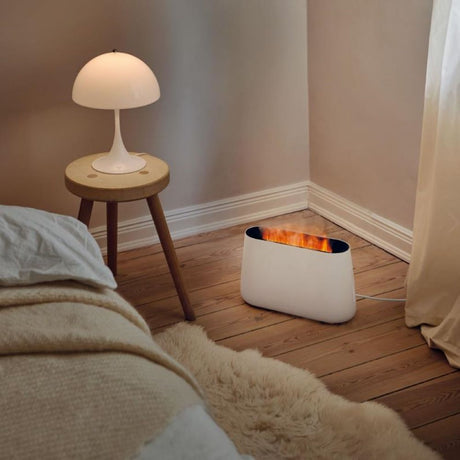 LED Humidifier & Aroma Diffuser Ben with fireplace effect light in a cozy bedroom setting.