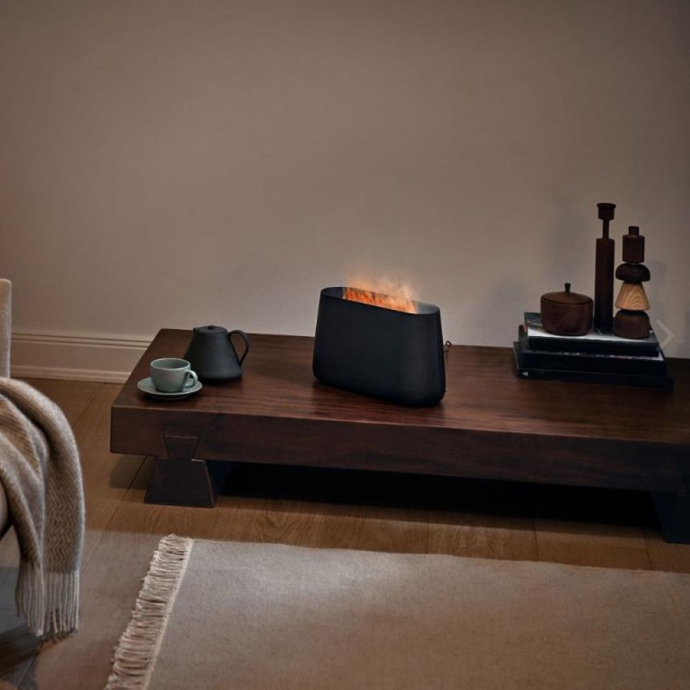 Humidificateur d'air LED & diffuseur d'arômes Ben avec effet lumière de cheminée sur une table basse dans un salon confortable.
