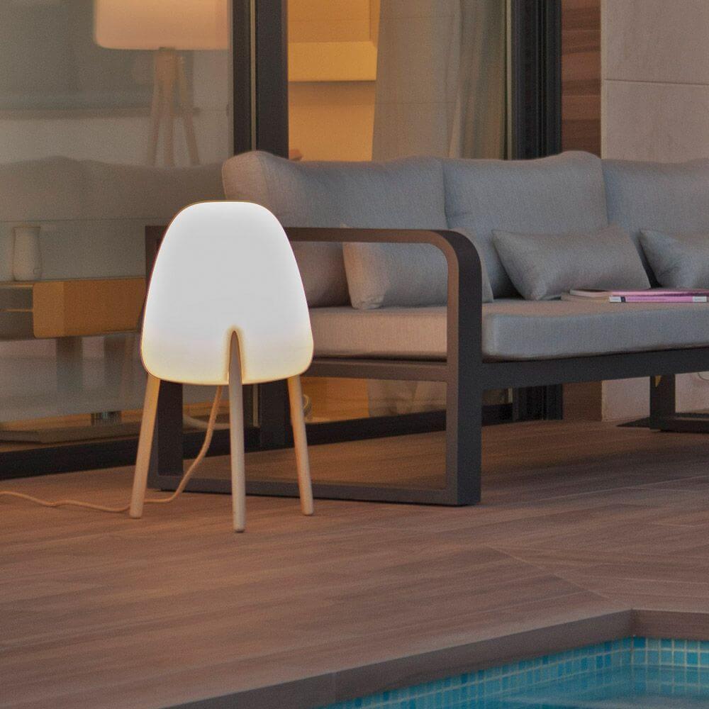 Rocket Dreibein-Tischleuchte in modernem Ambiente neben einem Sofa am Pool.