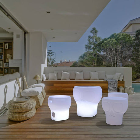 LED-Candeeiro solar de assento Calvin com design de caveira em ambiente exterior moderno sobre terraço de madeira.