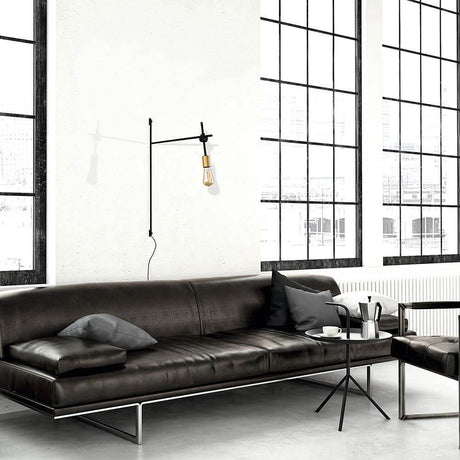 Retro wall light Axis Black on a wall above a modern sofa in a stylish room.
