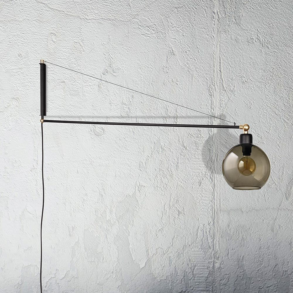 Wandleuchte Crane für die Steckdose Schwarz an einer Wand montiert mit Glaskugel.