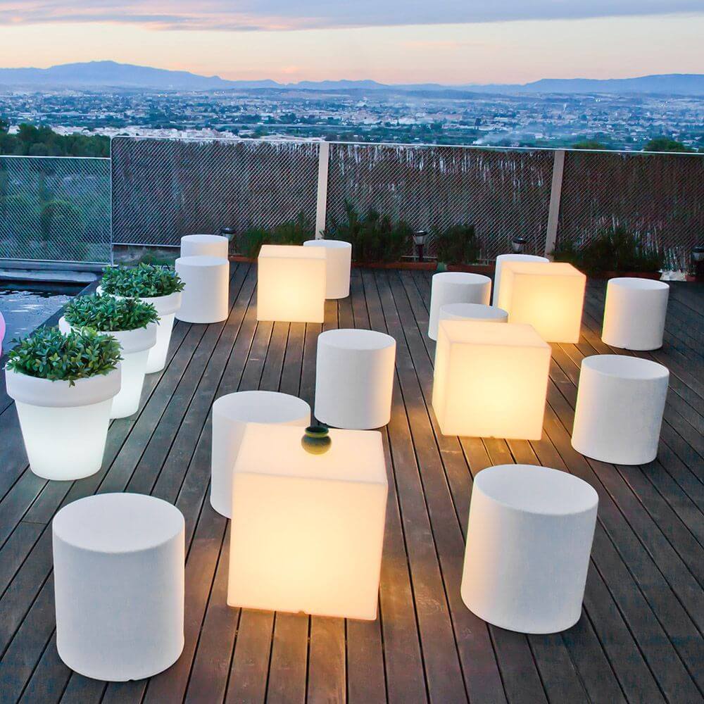 Beleuchtete Topfleuchte Magnolia Ø 45cm und dekorative Sitzmöbel auf einer Terrasse mit Blick auf die Stadt.