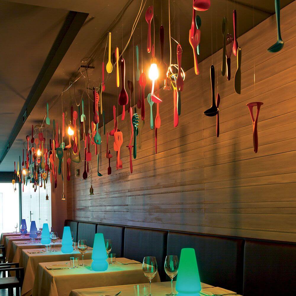 Ein modernes Restaurant mit bunten Küchenutensilien als Dekoration und stimmungsvollem Licht.