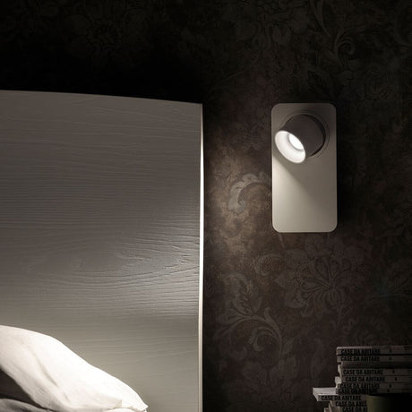 Beebo W LED wall light on a wall next to a bed, stylish lighting for modern living.