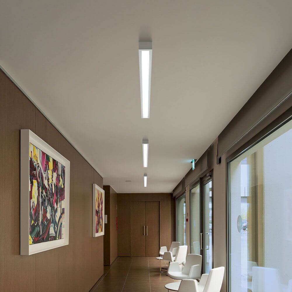 Moderne LED-Deckenleuchte im eleganten Design, installiert in einem stilvollen Raum mit Holzwänden.