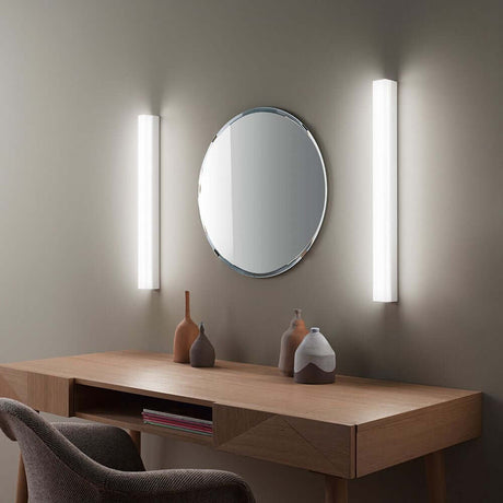 Kioo LED-Wandleuchte Big an einer Wand über einem modernen Tischspiegel in einem stilvollen Raum.
