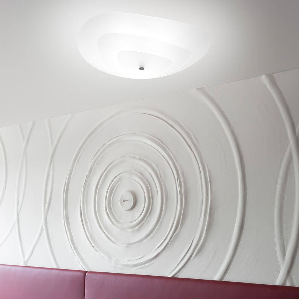 Moledro S Deckenleuchte an einer dekorativen Wand in einem modernen Raum.