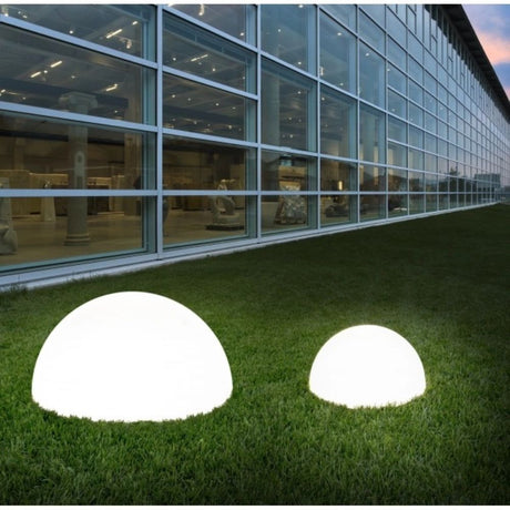 Ohps FL LED-Bodenleuchte für außen auf grünem Gras neben einem modernen Gebäude.