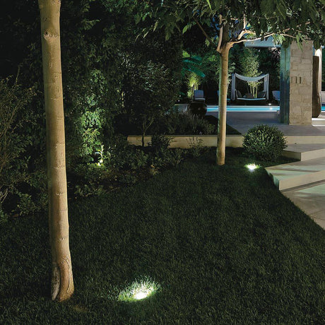 Schön beleuchteter Außenbereich mit Texo RJ Uplights, die den Garten und die Bäume hervorheben.