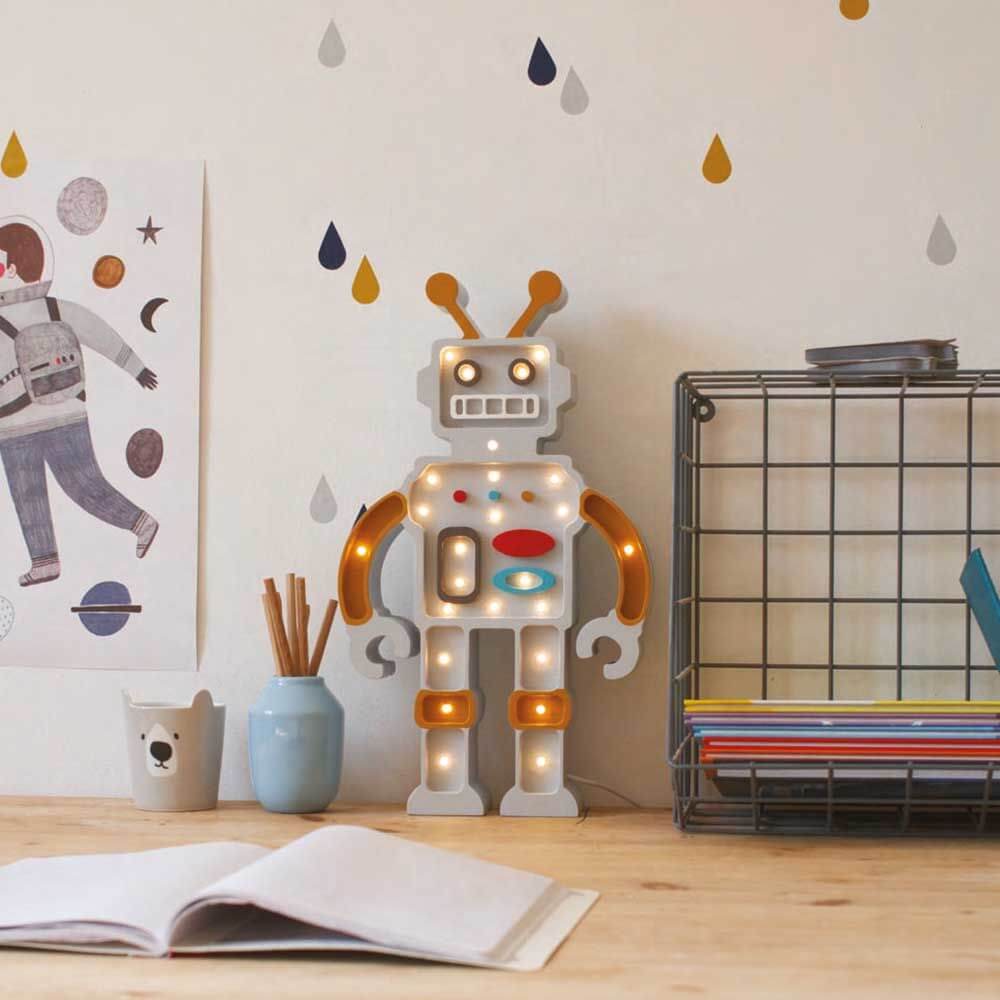 Kinder Wand- & Tischleuchte Roboter auf einem Tisch mit bunten Dekorationen im Hintergrund.