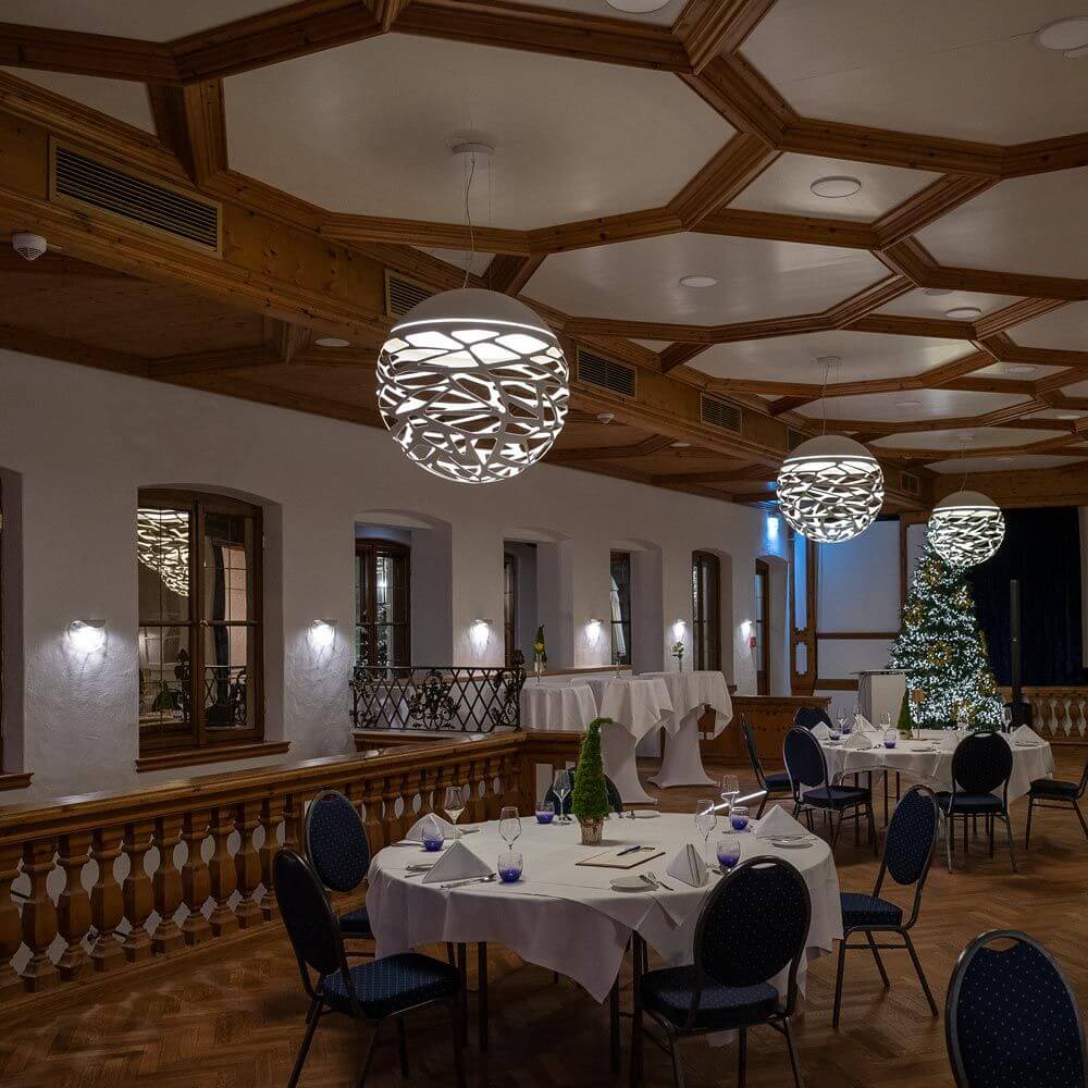 Elegantes Restaurant mit künstlerischen Lampen und festlichem Weihnachtsbaum, stilvoll dekorierten Tischen.