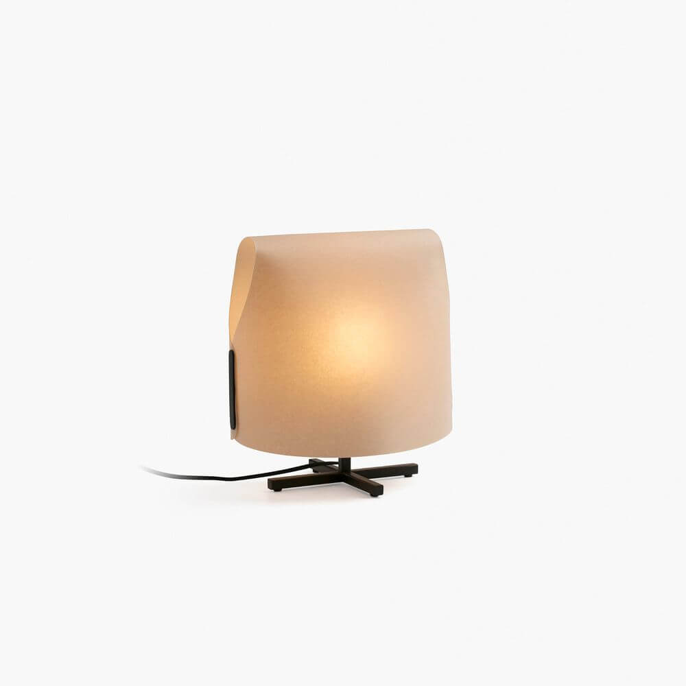 Luang Tischleuchte mit minimalistischer Struktur und weichem Licht auf einem modernen Tisch.