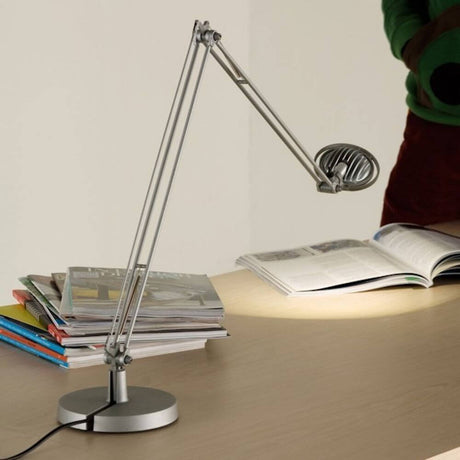Luceplan Berenice Schreibtischlampe auf einem Tisch mit Magazinen, leuchtend, modern und praktisch.
