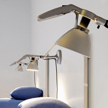 Luceplan Fortebraccio wall and ceiling spotlight Ø 16cm in a modern design above beds with blue cushions.