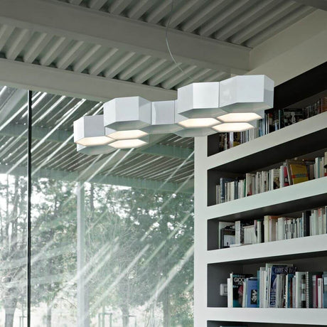 Luceplan Honeycomb LED Hängeleuchte mit 12 Waben 3000K Weiß über einem Bücherregal in modernem Raum.